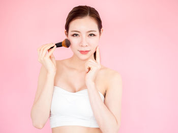 Portrait of a beautiful young woman over pink background