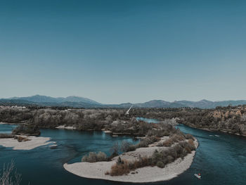 Scenic view of river and mountains against clear blue sky