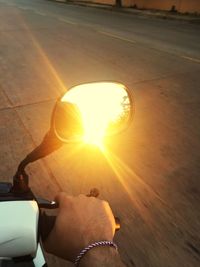 Close-up of hand against sun at sunset