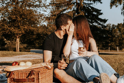 One  young couple kissing covering their faces with their hands and holding glasses of champagne 