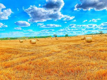 Hay bales on field against sky