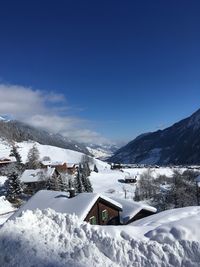 Snow covered buildings by mountain against sky