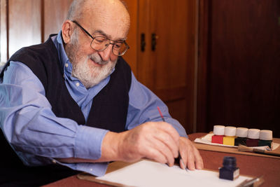 Senior man writing on paper at table