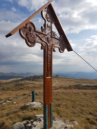 Traditional cross on field against sky