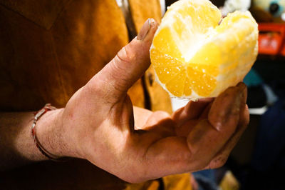 Mid section of person holding peeled orange