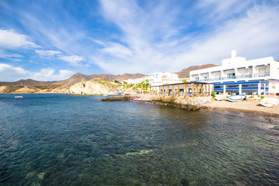 Scenic view of sea by buildings against sky