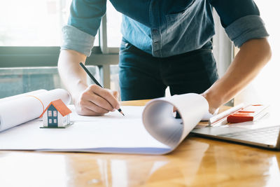 Midsection of man holding paper while sitting on table