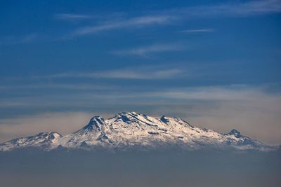 Scenic view of snow covered mountains against blue sky