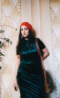 Portrait of beautiful young woman standing against wall