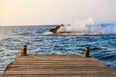 Pier over sea against sky during sunset