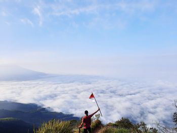 Rear view of man standing on mountain against sky