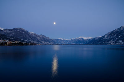 Scenic view of lake and snowcapped mountains against sky at night
