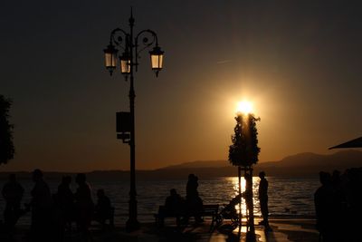 Silhouette people by sea against sky during sunset