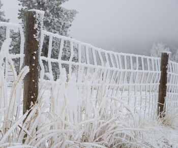 Wooden post on snow covered field against sky