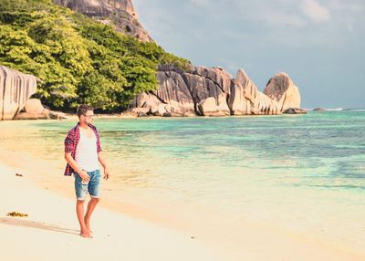 Full length of man standing at beach against sky