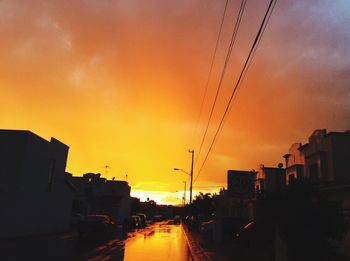 Vehicles on road against orange sky during sunset