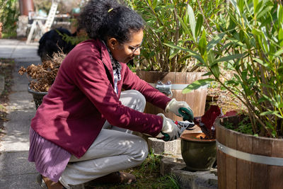 Side view of woman gardening with tool in yard