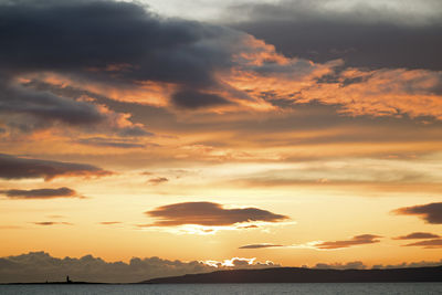 Scenic view of sea against dramatic sky during sunset