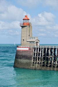 Lighthouse by sea against sky