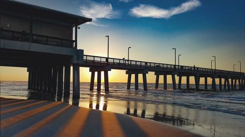 Pier over sea against sky during sunset