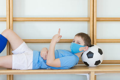 Boy wearing mask lying down on football