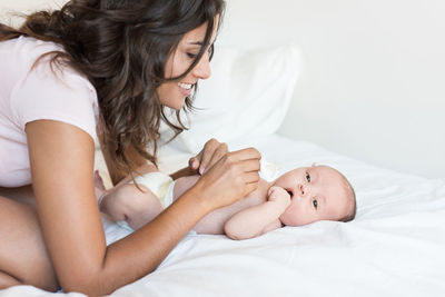 Midsection of woman with baby lying on bed