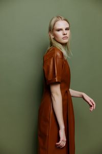 Portrait of young woman standing against wall