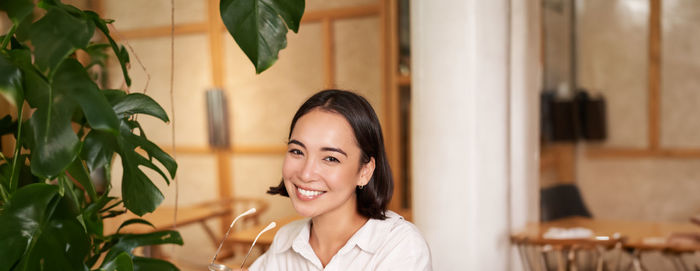 Portrait of young woman standing against wall