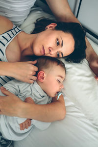 Close-up of man and woman with baby on bed at home