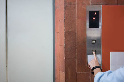 Person holding glass against wall