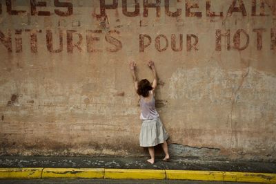 Rear view of woman standing against graffiti wall