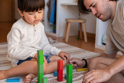 Son playing with puzzle while sitting with father at home