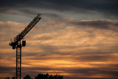 Low angle view of silhouette crane against sky during sunset