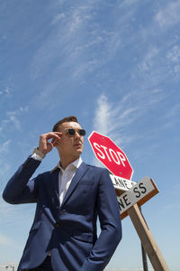 Low angle view of young man standing against sky