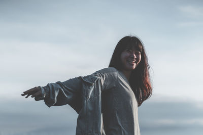 Portrait of smiling young woman standing against sky