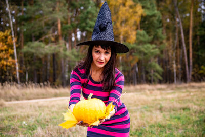 Witch with pumpkin in the autumn forest. halloween party concept