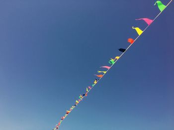 Low angle view of buntings against clear blue sky