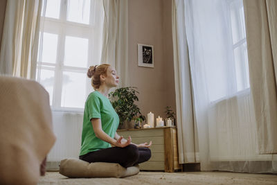 Woman with eyes closed practicing breathing exercise at home