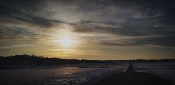 Scenic view of snowy field against sky during sunset