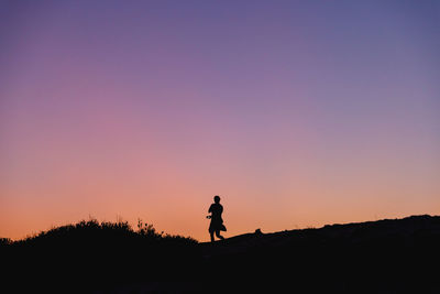 Silhouette of a woman standing against a clear sky during sunset