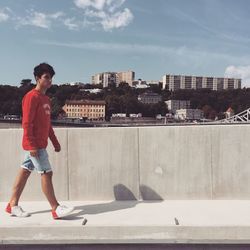 Full length of man standing by retaining wall against sky