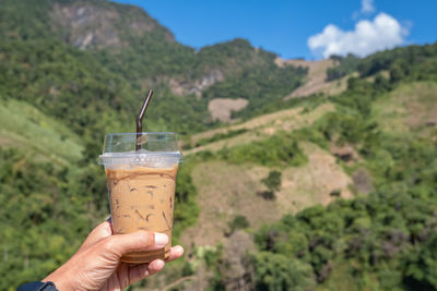 Midsection of person holding ice cream against mountain