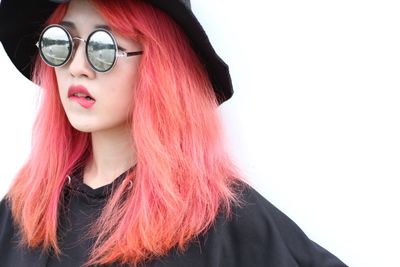 Portrait of beautiful woman wearing sunglasses and hat standing against white background