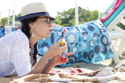 Beautiful woman blowing soap bubbles at the beach, close up portrait