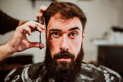 Cropped hands of barber grooming customer in salon