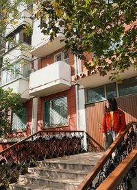 Woman standing by railing against building