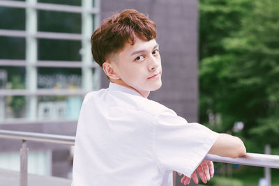 Portrait of boy standing against railing