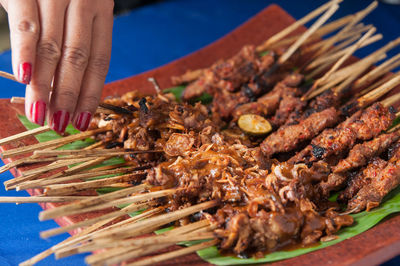 Midsection of person on satay or barbecue grill