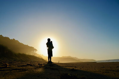 Dad and baby carrier in beach sunset