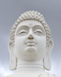 Low angle view of buddha statue against sky